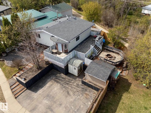 Expansive rear deck with railing, a dedicated fire pit area featuring built-in seating, and a gravel parking pad - 4759 48 Street, Onoway, AB - Outdoor With Deck Patio Veranda