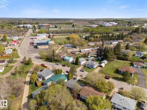 Aerial perspective showcasing a community with varied residential properties, surrounding green spaces, and a paved road network - 4759 48 Street, Onoway, AB - Outdoor With View