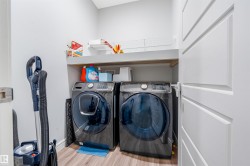 Dedicated laundry area featuring wood-finish flooring, white walls, and a built-in shelving unit for storage - 