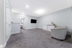 Spacious carpeted room featuring light gray walls, white baseboards, recessed lighting, and a white paneled door - 