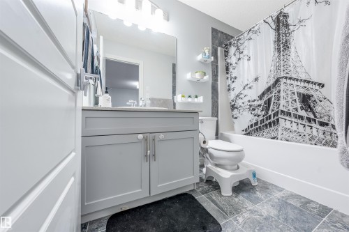 Full bathroom featuring a single vanity with gray cabinetry, a rectangular sink, and a light-colored countertop - 1024 Daniels Loop, Edmonton, AB 