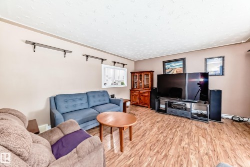 Spacious living area featuring wood-finish flooring, neutral wall tones, and overhead textured ceiling - 4006 115 Avenue, Edmonton, AB 