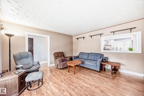 Living area featuring wood-finish flooring, neutral wall tones, and a pass-through window - 4006 115 Avenue, Edmonton, AB 