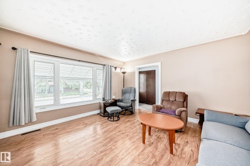 Living area featuring wood-finish flooring, light beige walls, and white baseboards - 4006 115 Avenue, Edmonton, AB 