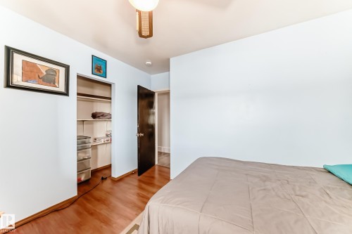 Room featuring wood-finish flooring, light blue walls, and a recessed closet with built-in shelving - 4006 115 Avenue, Edmonton, AB 