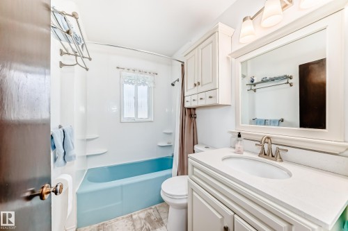 Bathroom featuring a blue bathtub, white shower surround, and a window with white trim - 4006 115 Avenue, Edmonton, AB 