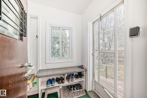 Entryway featuring a wood door, white walls, and a sliding glass door providing outdoor access - 4006 115 Avenue, Edmonton, AB 