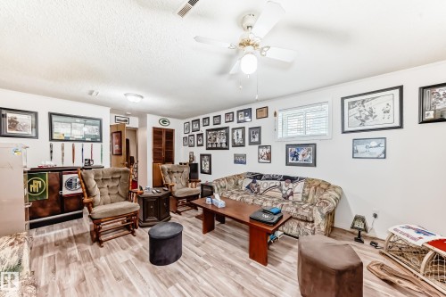 Finished basement area featuring wood-finish flooring, white walls, and a recessed window with blinds - 4006 115 Avenue, Edmonton, AB 