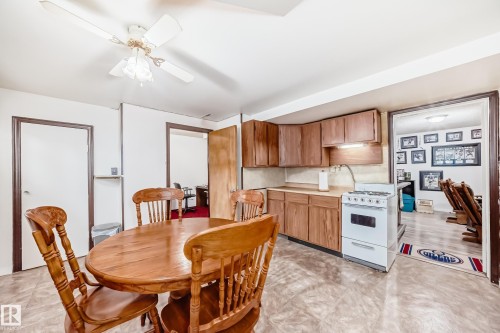 Kitchenette featuring wood-finish cabinetry, solid surface countertops, and a white freestanding gas range - 4006 115 Avenue, Edmonton, AB 