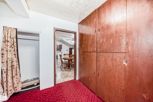 Built-in wood-finish cabinetry, red patterned carpeting, and a doorway opening to an additional room - 4006 115 Avenue, Edmonton, AB 
