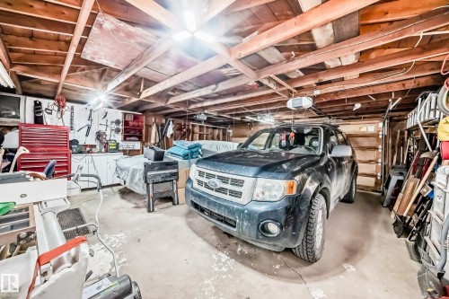 Utility garage with exposed wood beam ceiling, concrete flooring, and ample storage solutions - 4006 115 Avenue, Edmonton, AB 