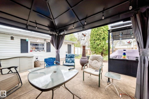 Covered concrete patio with overhead lighting, privacy curtains, and a built-in outdoor kitchen counter - 4006 115 Avenue, Edmonton, AB 