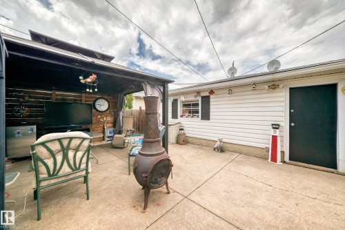 Paved patio area featuring a covered gazebo structure with a wood-slat back wall, a wall-mounted television, and a built-in outdoor refrigerator - 4006 115 Avenue, Edmonton, AB 