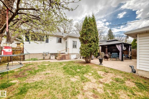 Expansive backyard featuring a patio area with a covered gazebo, mature trees, and a wooden fence - 4006 115 Avenue, Edmonton, AB 