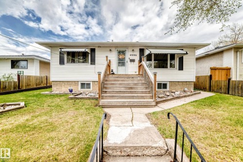 White siding exterior with a wood-tone staircase and handrails leading to the front entry - 4006 115 Avenue, Edmonton, AB 