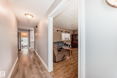 Interior hallway featuring wood-finish flooring, light grey painted walls, and white baseboards - 4006 115 Avenue, Edmonton, AB 