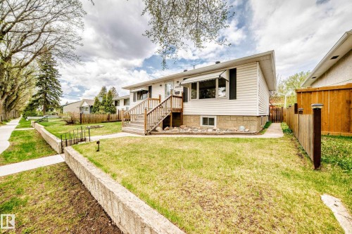 Two-story residence featuring white siding, a wood-finish front deck with stairs, and a partial stone facade - 4006 115 Avenue, Edmonton, AB 