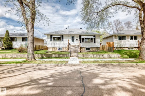Single-story residence featuring white siding, a contrasting dark roof, and a prominent front entrance with stairs - 4006 115 Avenue, Edmonton, AB 