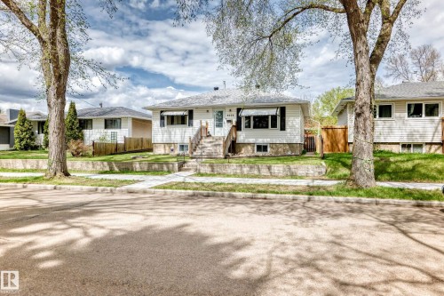 White siding exterior with a pitched roof, front entry stairs, and a well-maintained lawn - 4006 115 Avenue, Edmonton, AB 