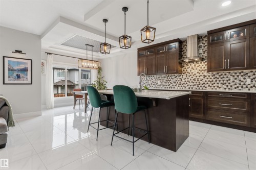 Contemporary kitchen featuring dark wood cabinetry, a mosaic tile backsplash, and a central island with a light-colored countertop - 3312 11 Avenue, Edmonton, AB - Indoor