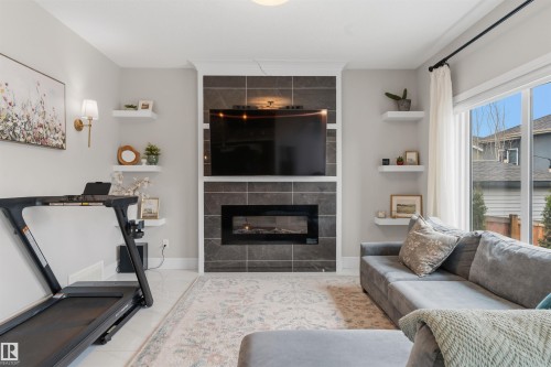 Living space featuring a tile-surround fireplace with a built-in electric insert, crown molding, and large windows - 3312 11 Avenue, Edmonton, AB - Indoor Photo Showing Living Room With Fireplace