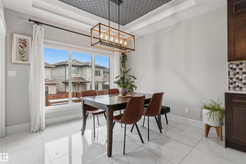 Bright dining area featuring a large picture window, white tile flooring, and a patterned tray ceiling - 3312 11 Avenue, Edmonton, AB - Indoor Photo Showing Dining Room