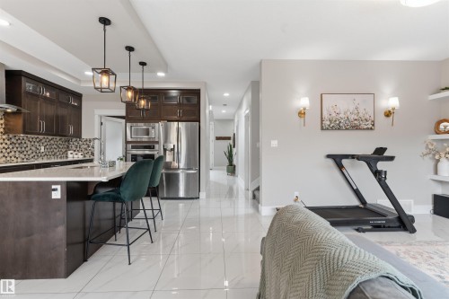 Kitchen featuring dark wood-finish cabinetry, stainless steel appliances, and a mosaic tile backsplash - 3312 11 Avenue, Edmonton, AB - Indoor