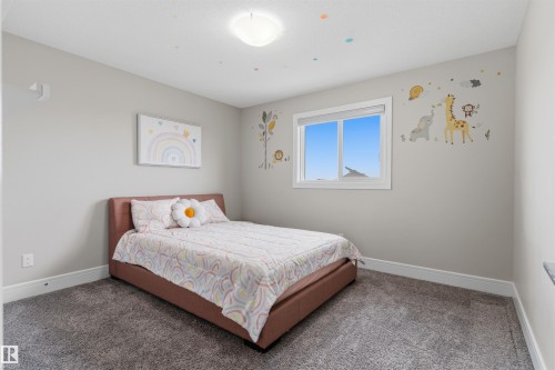 Neutral-toned bedroom featuring a large window, broad baseboards, and soft carpet flooring - 3312 11 Avenue, Edmonton, AB - Indoor Photo Showing Bedroom
