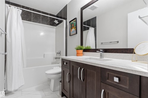 Bathroom featuring a dark wood-finish vanity with a light speckled countertop, under-mount sink, and chrome faucet - 3312 11 Avenue, Edmonton, AB - Indoor Photo Showing Bathroom