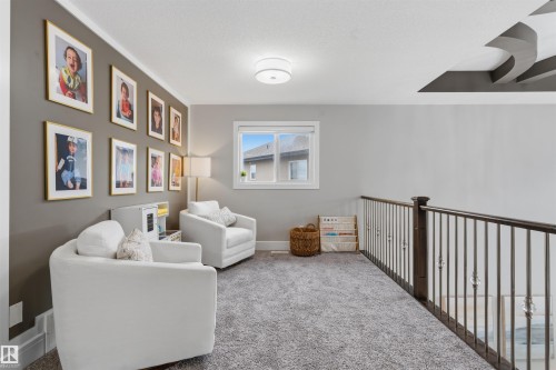 Loft area featuring a neutral color palette, plush grey carpeting, a window providing natural light, a decorative ceiling detail, and an open railing with ornate balusters - 3312 11 Avenue, Edmonton, AB - Indoor Photo Showing Other Room
