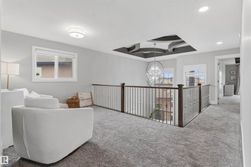 Open upper-level space featuring carpet flooring and a decorative recessed ceiling with an elaborate chandelier - 3312 11 Avenue, Edmonton, AB - Indoor Photo Showing Other Room