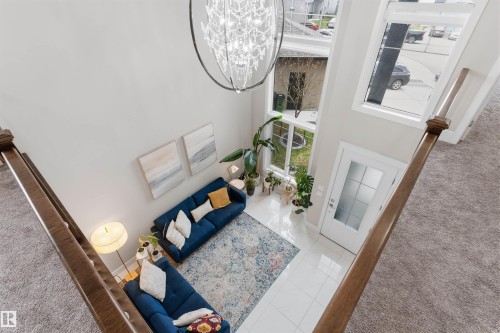 Soaring two-story living area featuring a grand chandelier, multiple large windows, and a white paneled door with frosted glass inserts - 3312 11 Avenue, Edmonton, AB - Indoor Photo Showing Other Room