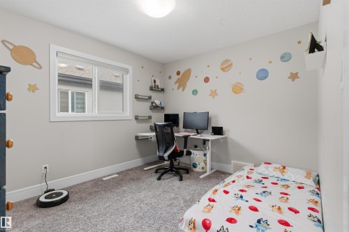 Carpeted room featuring a single window with white trim, a built-in floating desk system with shelves, and a ceiling-mounted light fixture - 3312 11 Avenue, Edmonton, AB - Indoor Photo Showing Bedroom