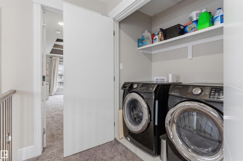 Dedicated laundry closet featuring a built-in shelf, front-loading washer, and dryer - 3312 11 Avenue, Edmonton, AB - Indoor Photo Showing Laundry Room
