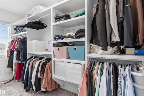 Custom closet system featuring multiple hanging rods, integrated shelving, built-in drawers, and a window for natural light - 3312 11 Avenue, Edmonton, AB - Indoor With Storage