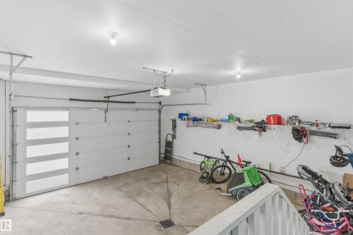 Two-car garage featuring a modern white garage door with frosted glass panels, concrete flooring, overhead lighting, and built-in wall shelving - 3312 11 Avenue, Edmonton, AB - Indoor Photo Showing Garage