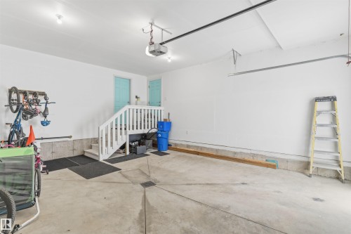 Concrete flooring garage with white painted walls, a white staircase with balusters, and two turquoise doors - 3312 11 Avenue, Edmonton, AB - Indoor Photo Showing Other Room