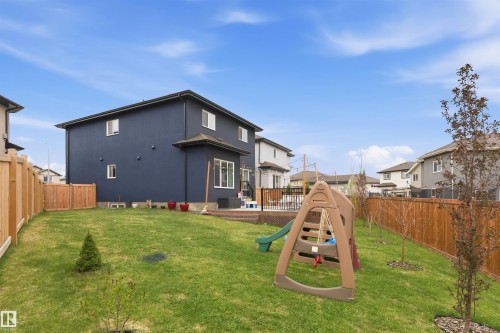 Spacious fenced backyard featuring a manicured lawn, a wooden deck with black railings, and mature perimeter trees - 3312 11 Avenue, Edmonton, AB - Outdoor