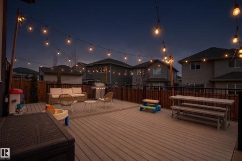 Expansive composite deck featuring string lighting, wood privacy fencing, and black metal railings - 3312 11 Avenue, Edmonton, AB -  With Deck Patio Veranda