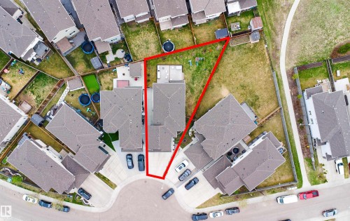 Aerial view of a residential property outlined in red, featuring a paved driveway, a private backyard space with a patio, and direct access to a paved pathway - 3312 11 Avenue, Edmonton, AB - Other