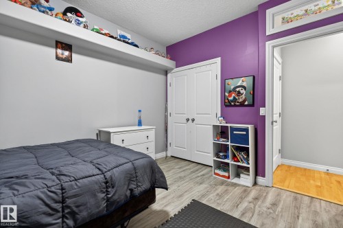 Bedroom featuring wood-finish flooring, a vibrant accent wall, and a built-in display shelf - 34 Valleyview Ridge, Fort Saskatchewan, AB - Indoor Photo Showing Bedroom