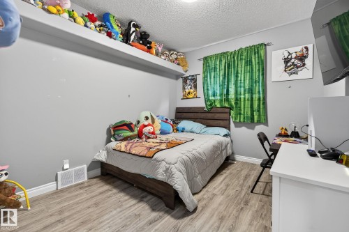 Grey wall tones complemented by wood-finish flooring - 34 Valleyview Ridge, Fort Saskatchewan, AB - Indoor Photo Showing Bedroom