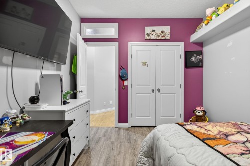 Interior room featuring plank flooring, a closet with bi-fold doors, a transom window, and a wall-mounted television - 34 Valleyview Ridge, Fort Saskatchewan, AB - Indoor Photo Showing Bedroom