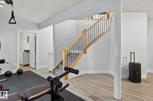 Hardwood staircase with wrought iron balusters - 34 Valleyview Ridge, Fort Saskatchewan, AB - Indoor Photo Showing Gym Room
