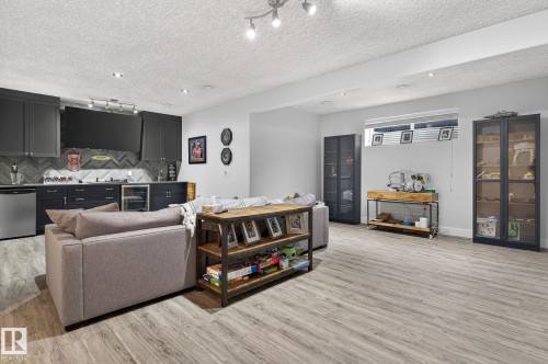 Entertainment area featuring wood-finish flooring, a built-in wet bar with dark cabinetry, herringbone-patterned backsplash, and recessed lighting - 34 Valleyview Ridge, Fort Saskatchewan, AB - Indoor