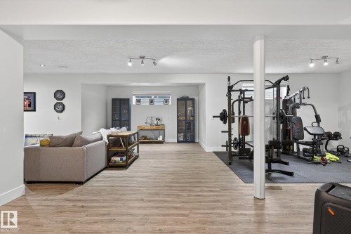 Open-concept lower level featuring wood-finish flooring, recessed lighting, and a neutral color palette - 34 Valleyview Ridge, Fort Saskatchewan, AB - Indoor Photo Showing Gym Room