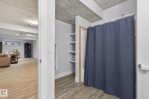 Full bathroom featuring a shower-tub combination, built-in shelving, and wood-finish flooring - 34 Valleyview Ridge, Fort Saskatchewan, AB - Indoor