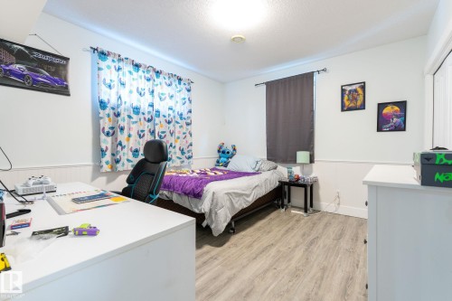 Room featuring light-toned wood-finish flooring, white walls with wainscoting, and a ceiling light fixture - 34 Valleyview Ridge, Fort Saskatchewan, AB - Indoor Photo Showing Bedroom