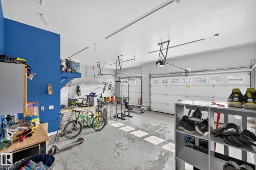Spacious garage featuring white sectional doors with upper window panels, ample overhead lighting, and painted concrete flooring - 34 Valleyview Ridge, Fort Saskatchewan, AB - Indoor Photo Showing Garage