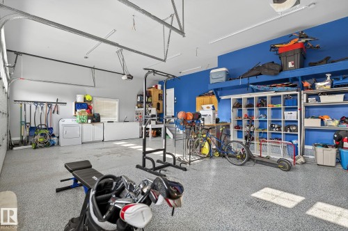 Spacious garage featuring an epoxy-coated concrete floor, bright overhead lighting, and extensive built-in shelving - 34 Valleyview Ridge, Fort Saskatchewan, AB - Indoor Photo Showing Garage